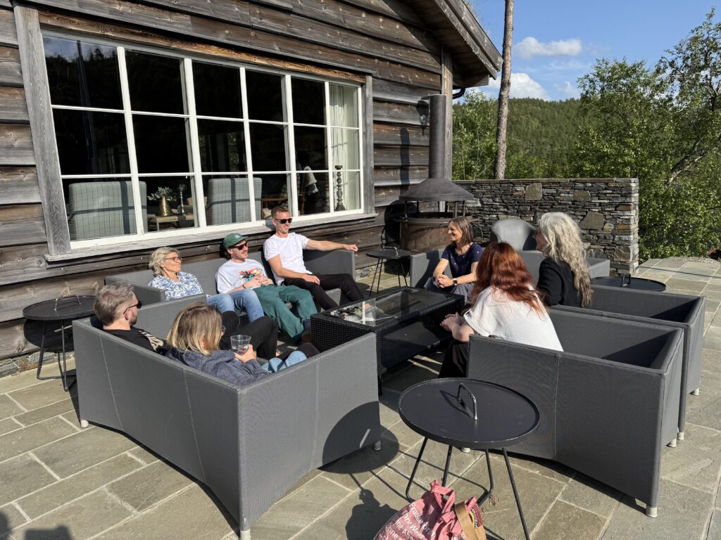 Sitzgruppe mit Menschen auf Terrasse vor einer großen Hütte in Norwegen